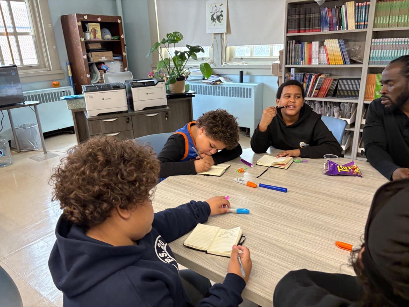 Elementary students write in notebooks during a facilitated classroom activity.