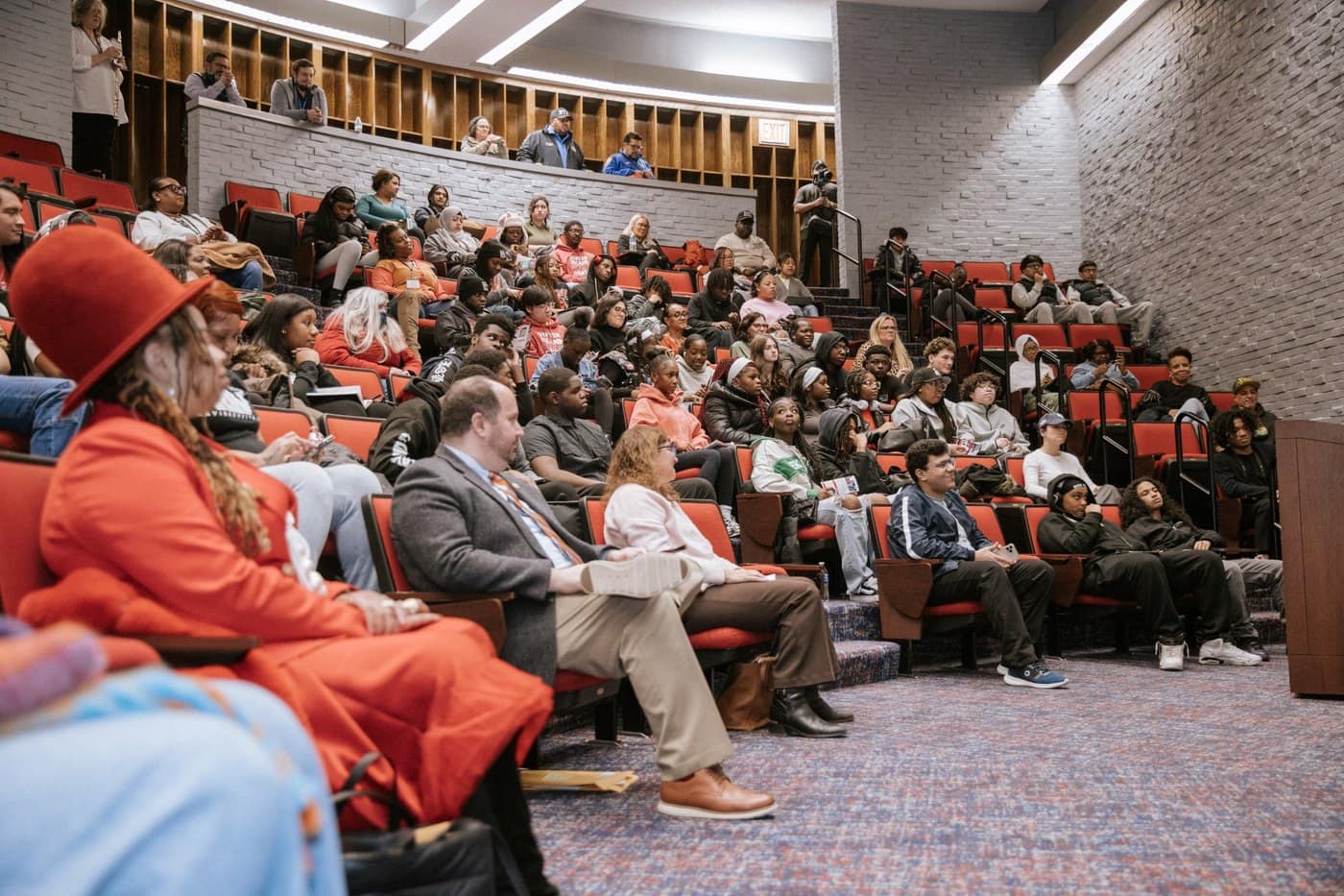 A wide overhead view shows a panel discussion and a full auditorium at the summit.