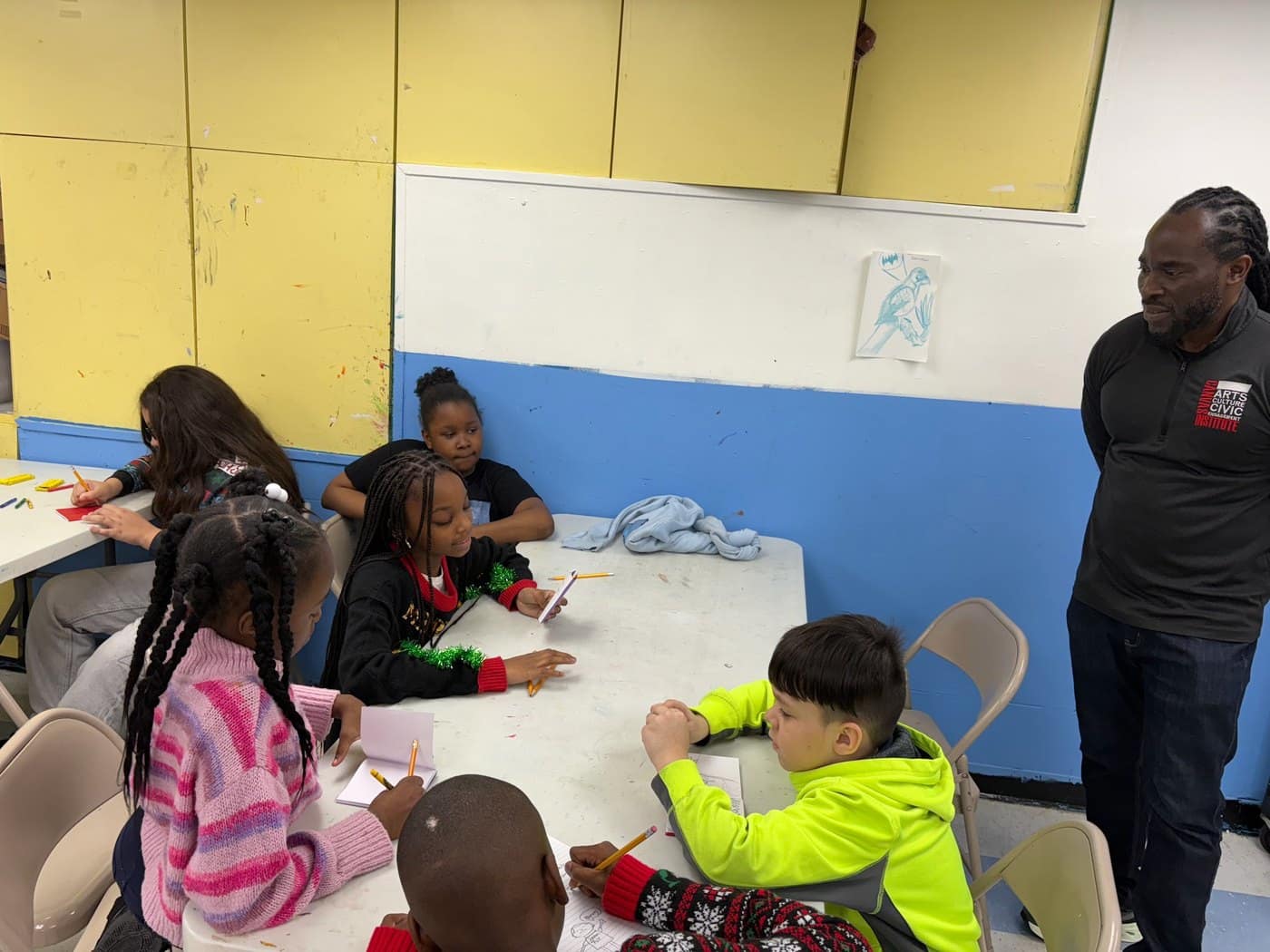 Young participants write in notebooks during a small-group workshop.