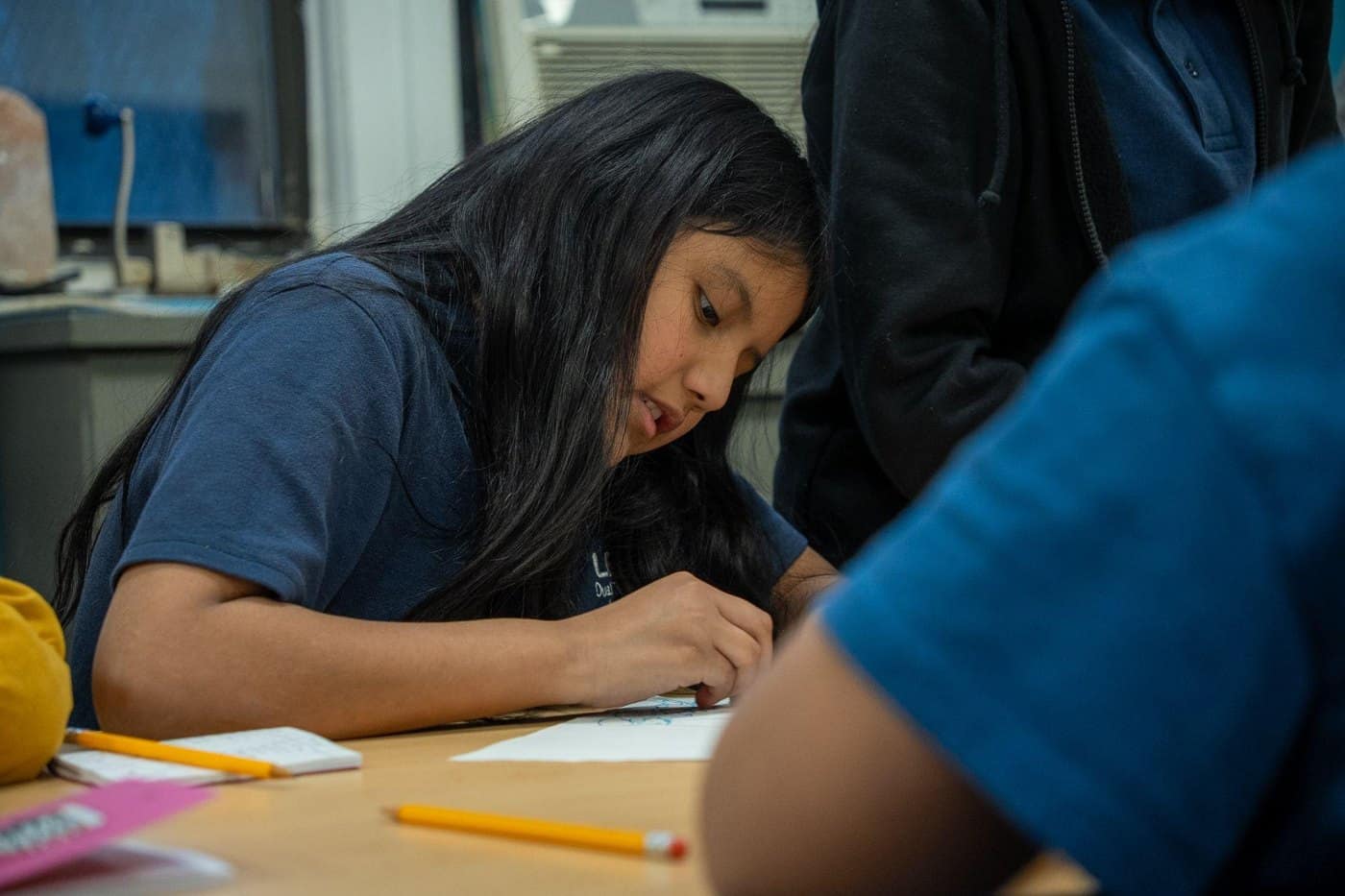 A student concentrates on a writing activity during a classroom workshop.
