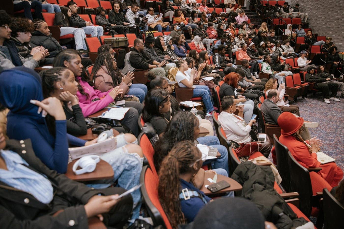 Young people and community members applaud during an auditorium session.